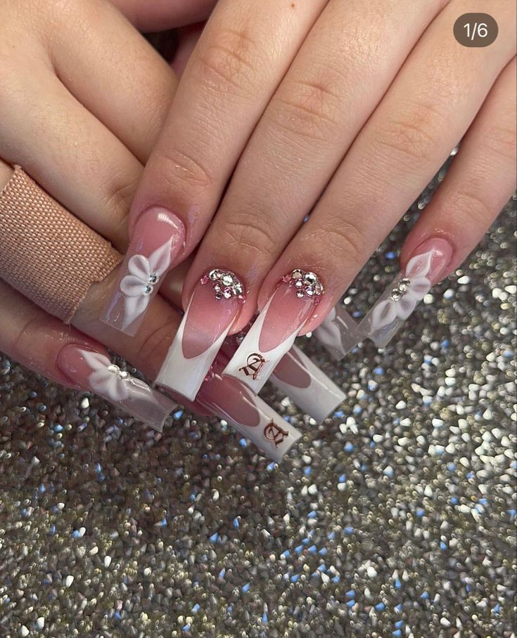 Chic Pink and White Nail Design with Floral Accents and Rhinestones.