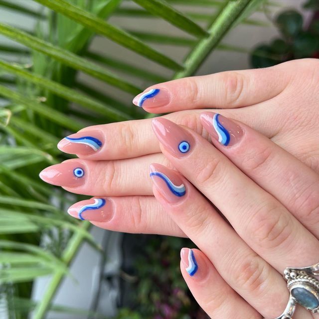 Elegant Soft Pink Nails with Dynamic Blue and White Wave Patterns and Intriguing Eye Motifs