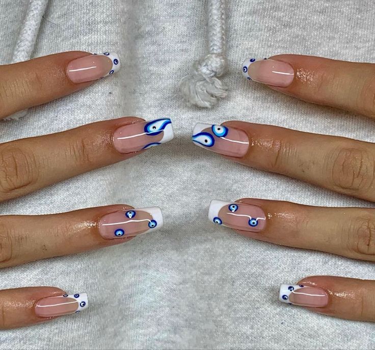 Chic Nail Design: Clear and White Tips with Unique Blue Eye Motifs for a Trendy Statement.