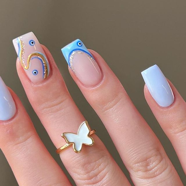 Chic Pastel Blue and Nude Nail Design with Artistic Swirls and Butterfly Ring Accent.