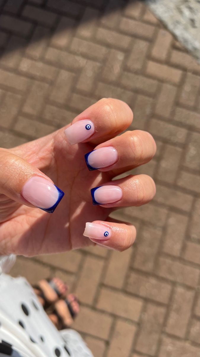 Chic Soft Pink Nails with Bold Blue Tips and Playful Eye Accents.