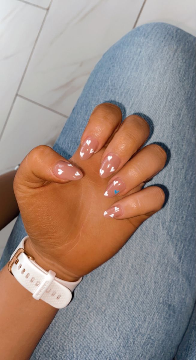 Chic Nude Nail Design with Delicate White Hearts and a Pop of Blue.