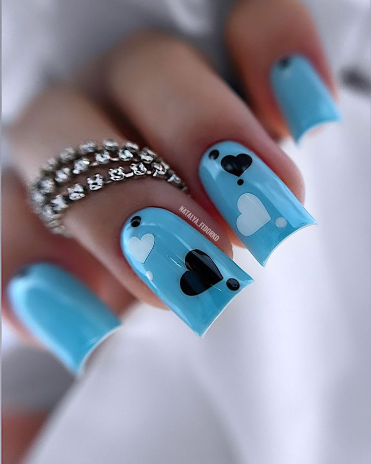 Vibrant Blue Nail Design with Playful Heart Shapes and Delicate Jewelry.