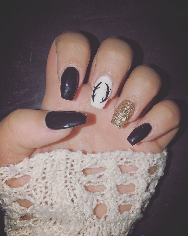 Chic Nail Design: Deep Black with White Antler Accent and Glittery Gold Glamour.