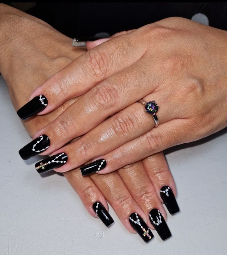 Sophisticated Black Nail Design with Intricate White and Gold Accents for Glamorous Occasions