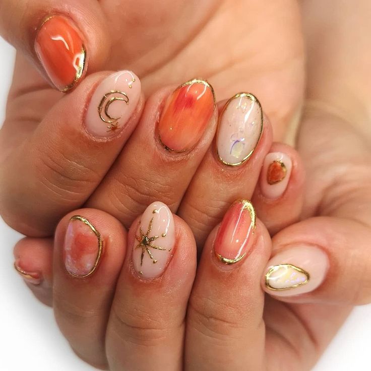 Elegant Orange and Nude Nail Design with Gold Accents and Celestial Floral Motifs.