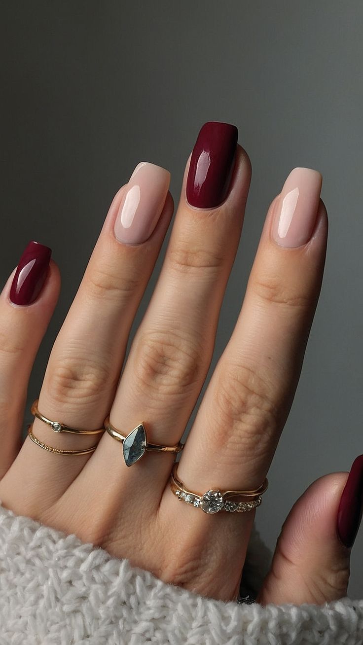 Chic Nail Design: Striking Deep Burgundy and Soft Nude with Gold Accents.