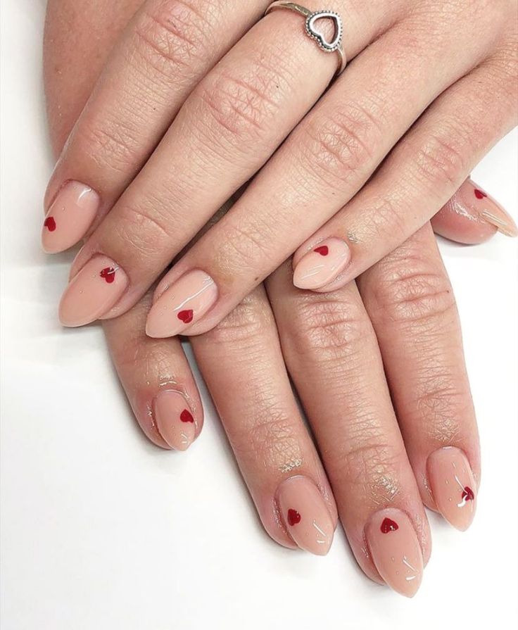 Charming Nude Nail Design with Playful Red Heart Accents.