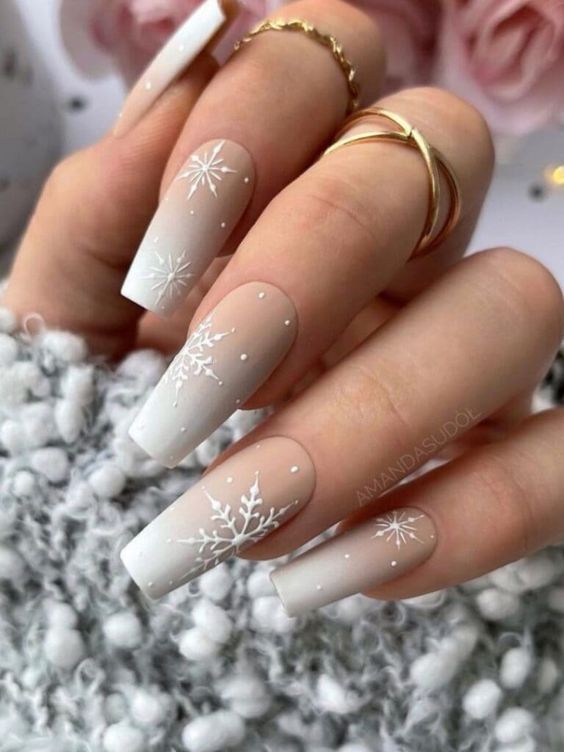 Elegant Winter Nail Design: Ombre Tips, Snowflakes, and Gold Accents.