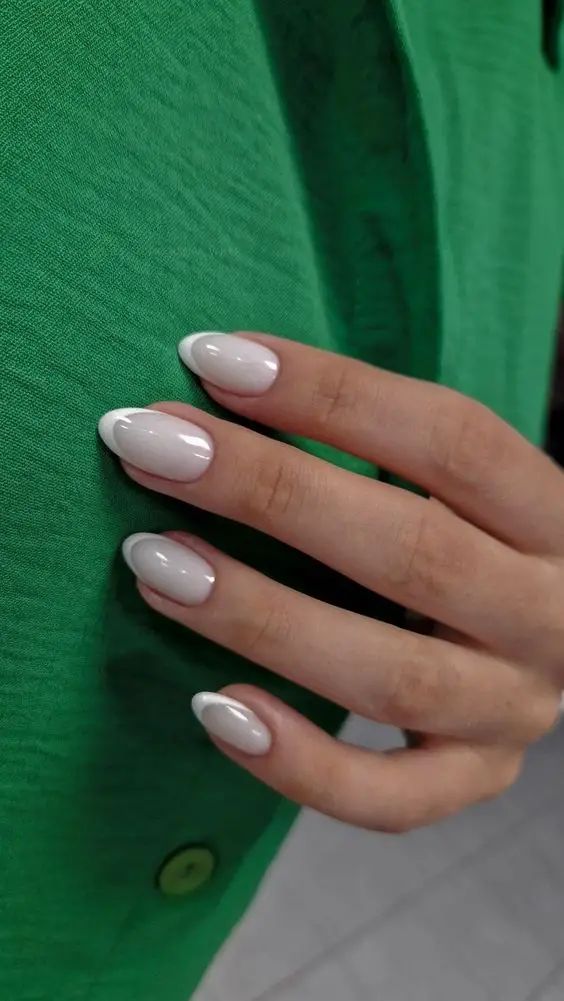 Sophisticated Almond-Shaped French Manicure on Vibrant Green Background.