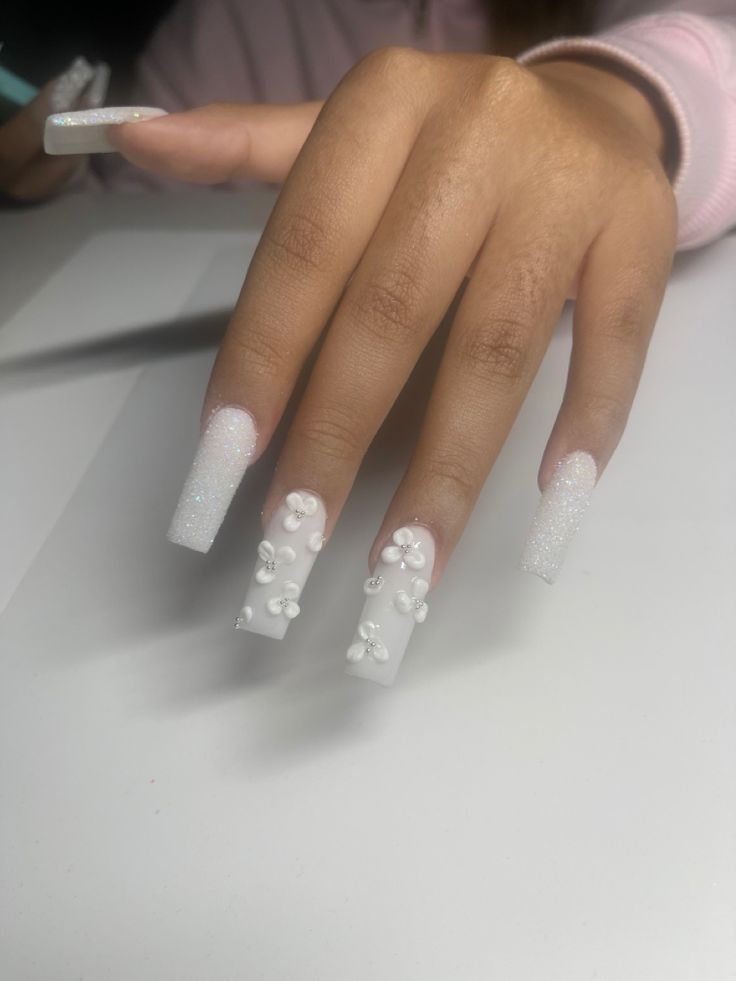 Chic Long Square Nails: Soft White Finish with Sparkly Floral Accents for a Modern, Playful Touch.