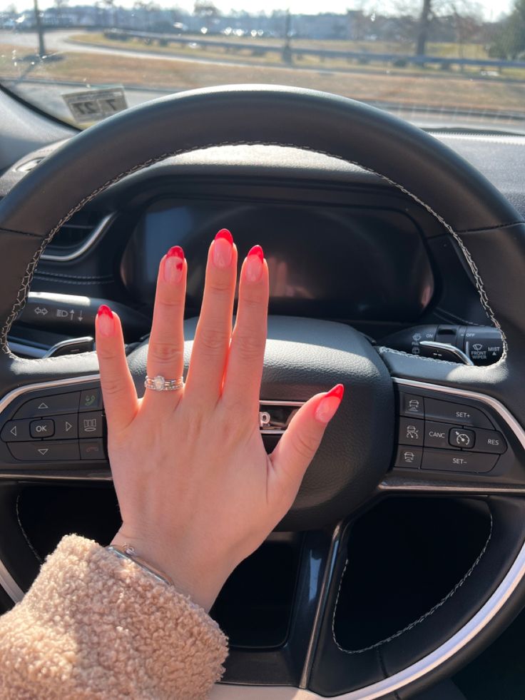 Elegant Vibrant Red French Tip Nail Design Enhances Glamour in a Car Interior.