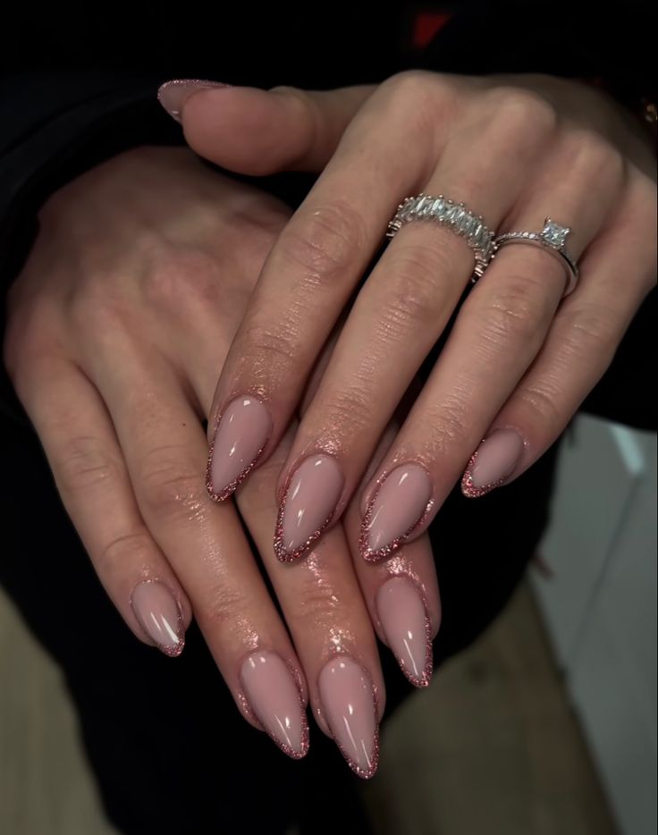 Sophisticated Nude Almond Nails with Glittery Pink Edges and Glamorous Accessories.