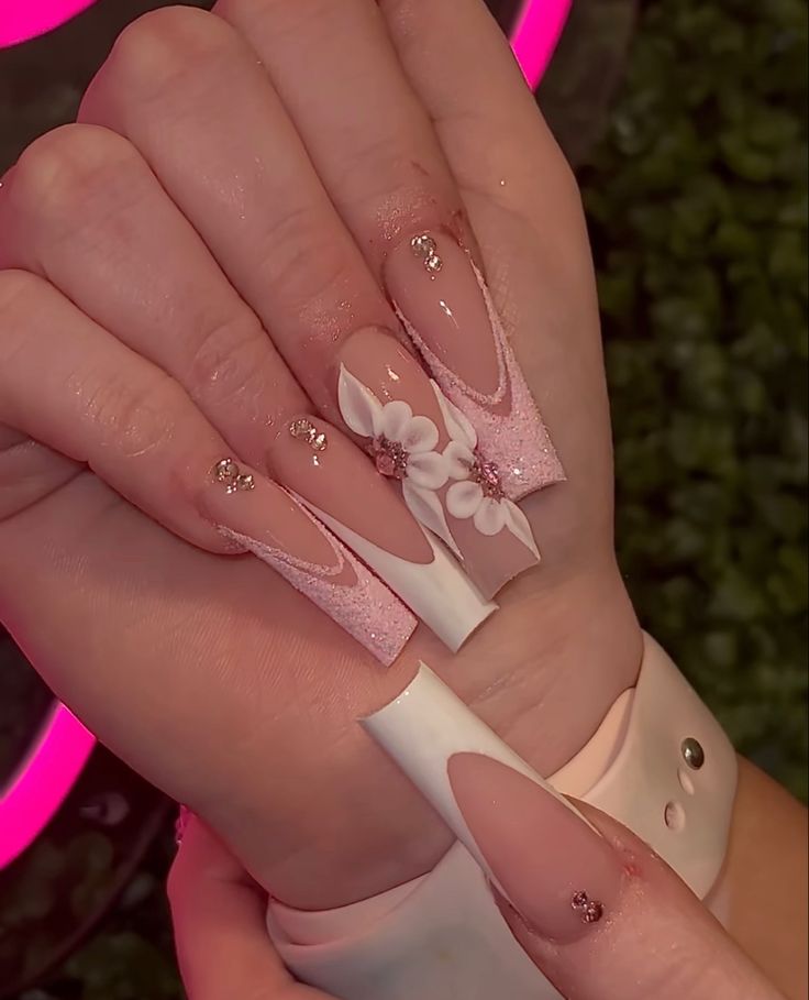 Glamorous Long Pink and White Pointed Nail Design with Floral Accents.