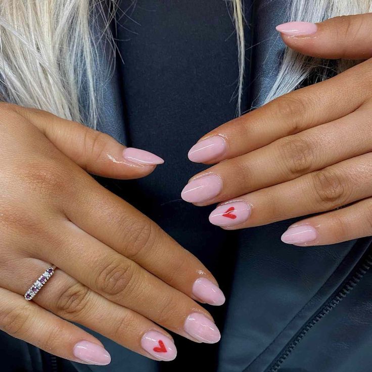 Chic Almond-Shaped Nails with Soft Pink Base and Playful Red Heart Accents.