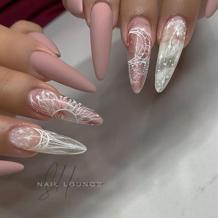 Elegant Almond Nail Design in Soft Pink and White with Artistic Lace and Celestial Patterns.