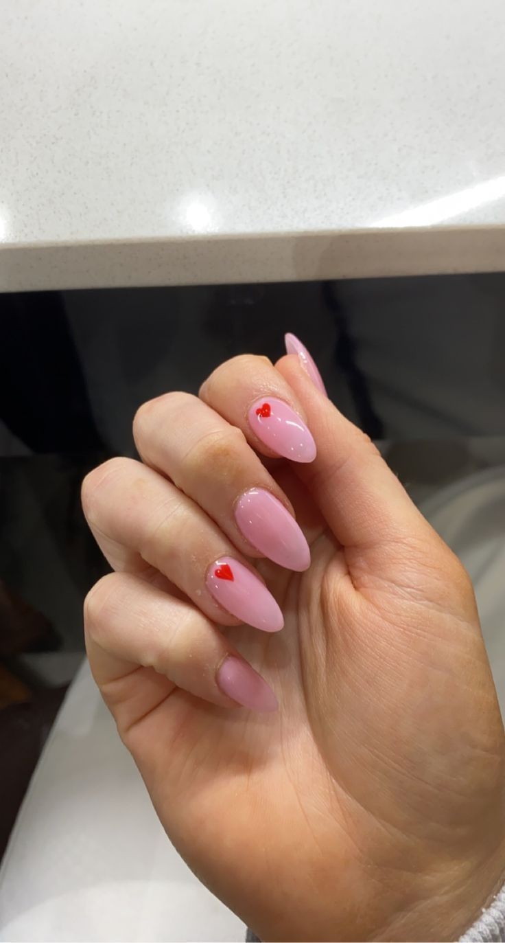 Charming Almond-Shaped Manicure with Glossy Soft Pink Polish and Playful Red Heart Accents