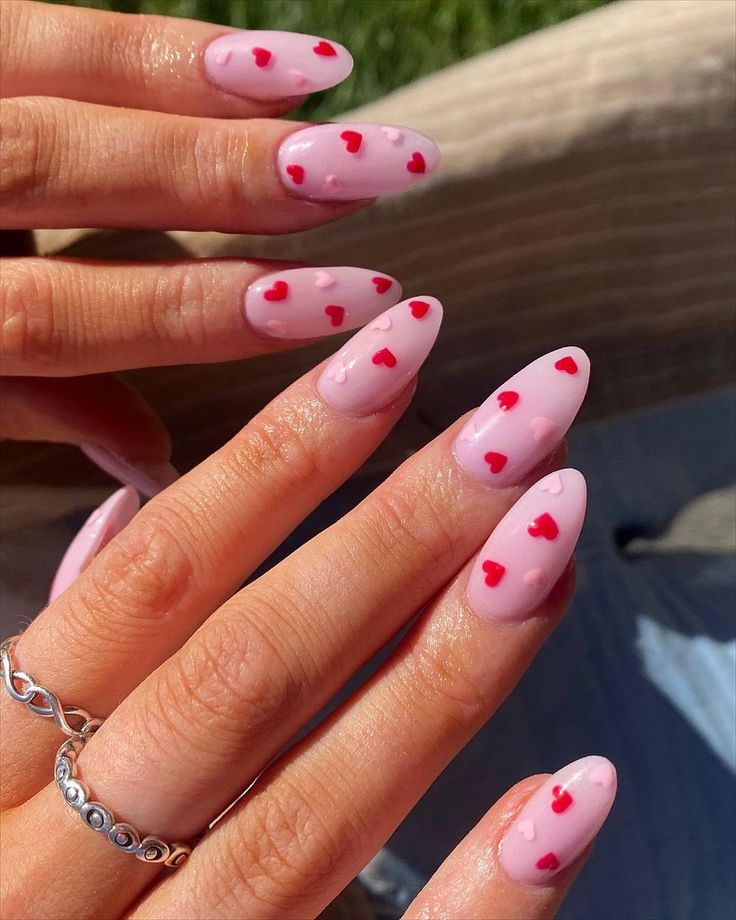 Charming Pink Manicure with Romantic Red Hearts for a Playful Touch.