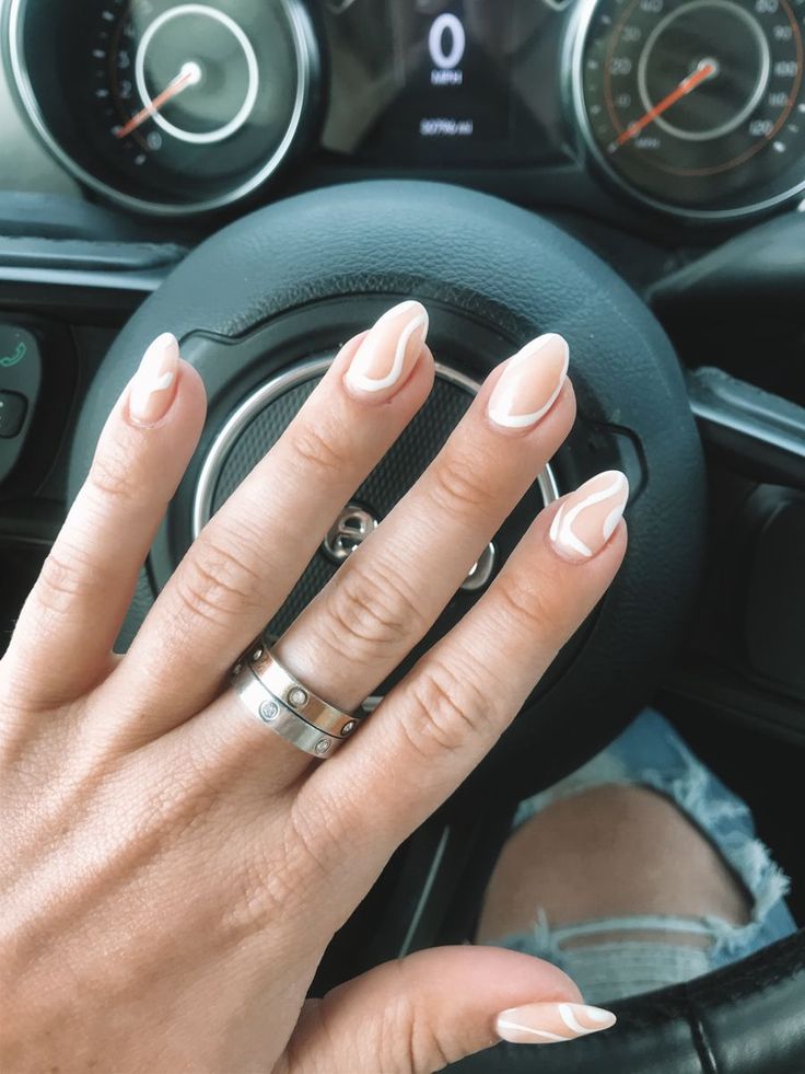 Sophisticated Almond-Shaped Nails with Soft Nude Base and Delicate White Swirls Enhanced by a Chic Silver Ring.