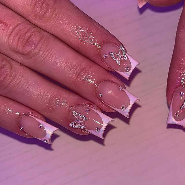 Translucent Pink Nail Design with White Tips and Butterfly Motifs Enhanced by Sparkling Rhinestones.