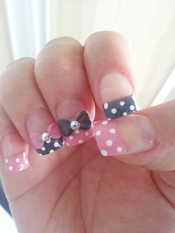 Whimsical Pink and Black Polka Dot Nail Design with Bows and Rhinestones.