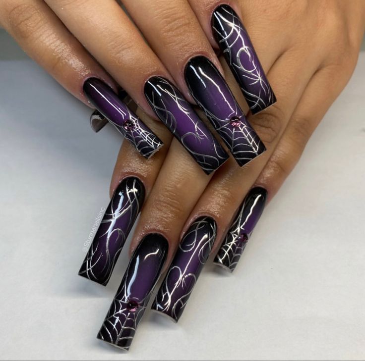 Elegant Halloween-Inspired Nail Art: Deep Purple and Glossy Black with Intricate Spiderweb Designs and Gem Accents.