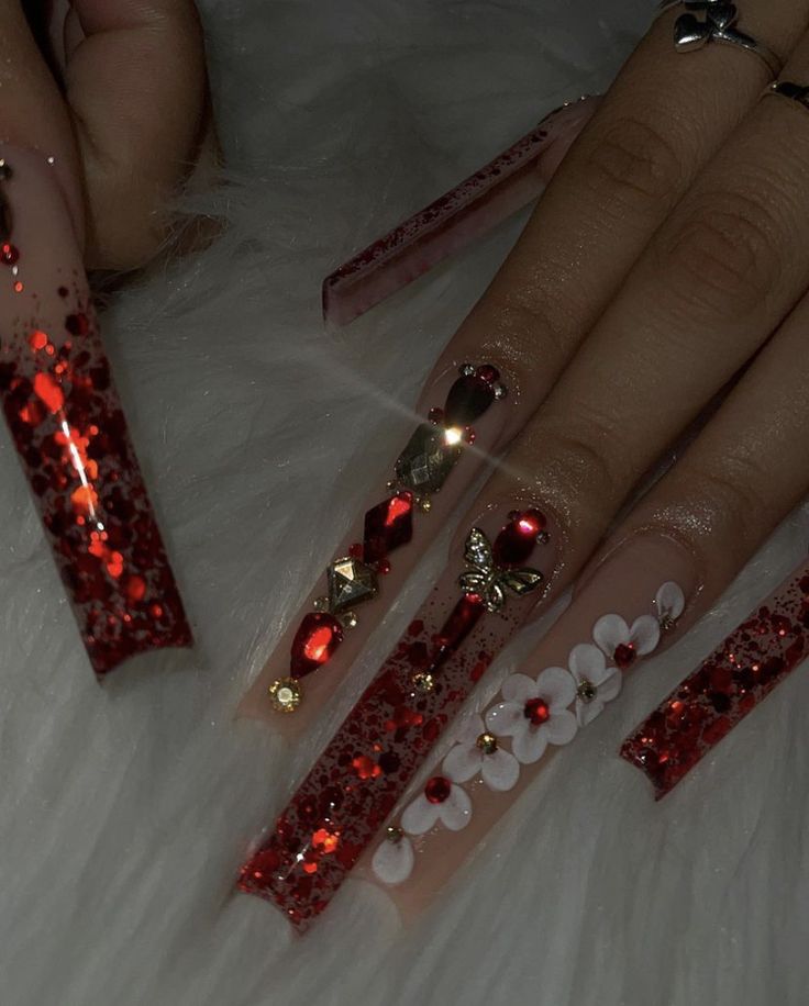 Glamorous Red Glittery Stiletto Nail Design with Luxurious Embellishments.