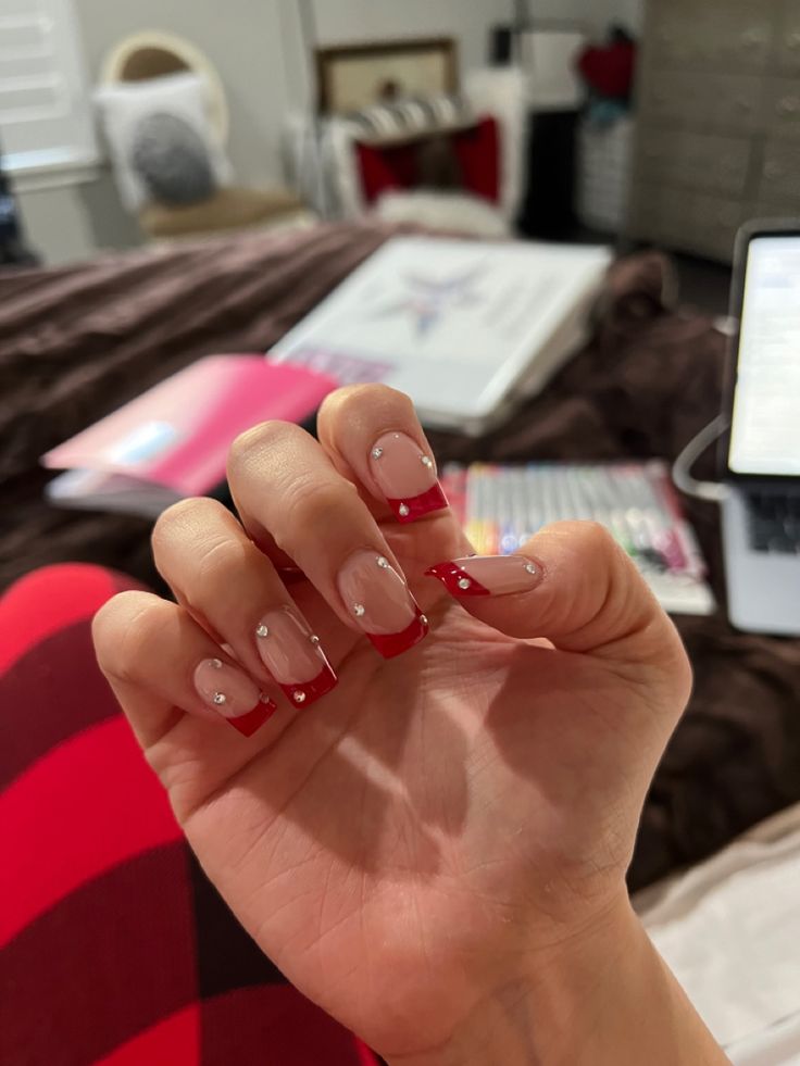 Striking Red French Tips with Delicate Rhinestones for a Sophisticated Nail Design.