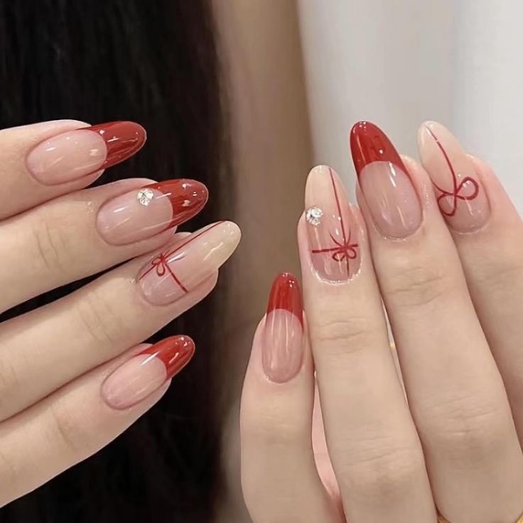 Chic Nail Design: Elegant Nude Base with Striking Red Tips and Glamorous Rhinestones