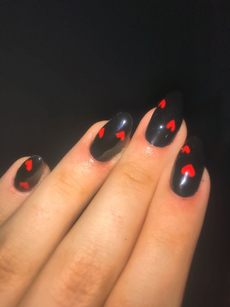 Bold Black Nail Design with Playful Red Heart Motifs for a Flirty and Elegant Look.