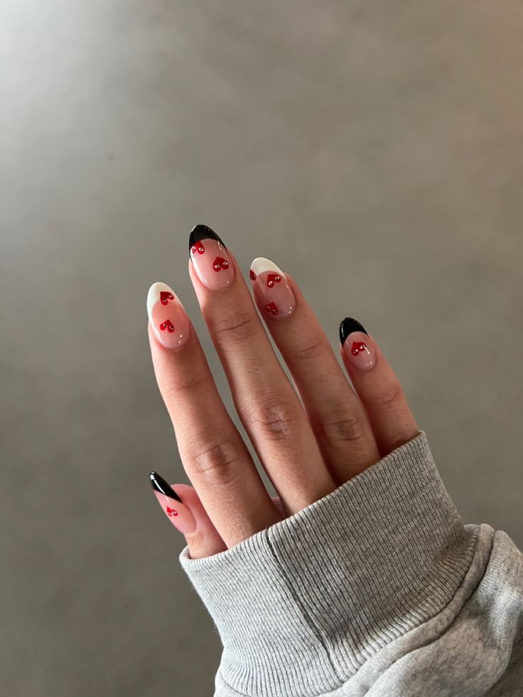 Charming Nail Design: Elegant Soft Pink Base with Striking Black Tips and Playful Red Cherry Accents.