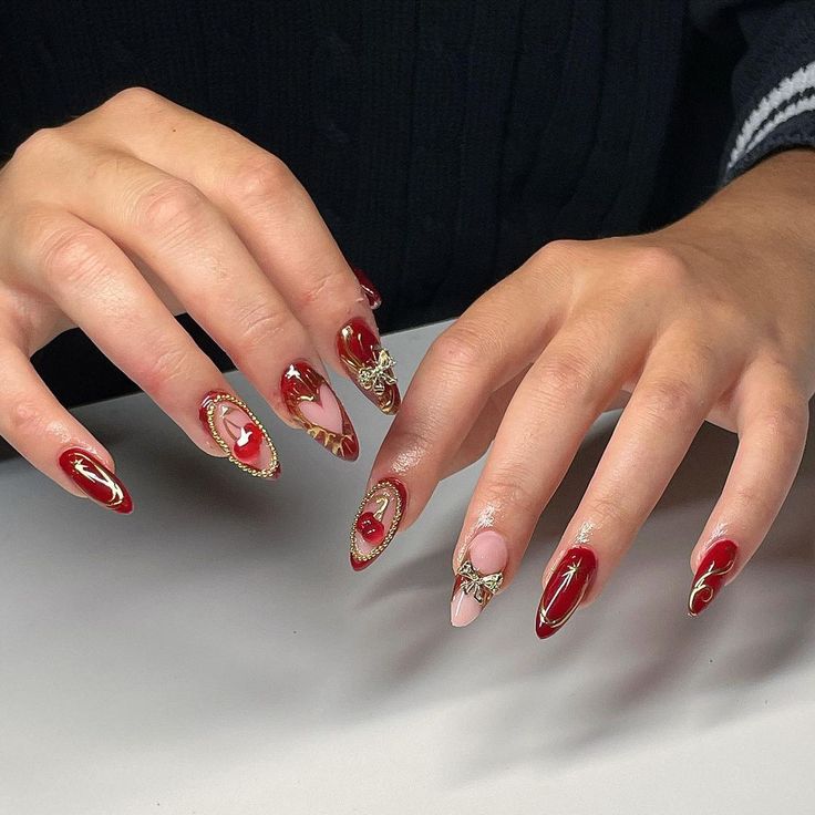 Sophisticated Red and Nude Nail Design with Intricate Gold Accents and Whimsical Touches for Special Occasions.