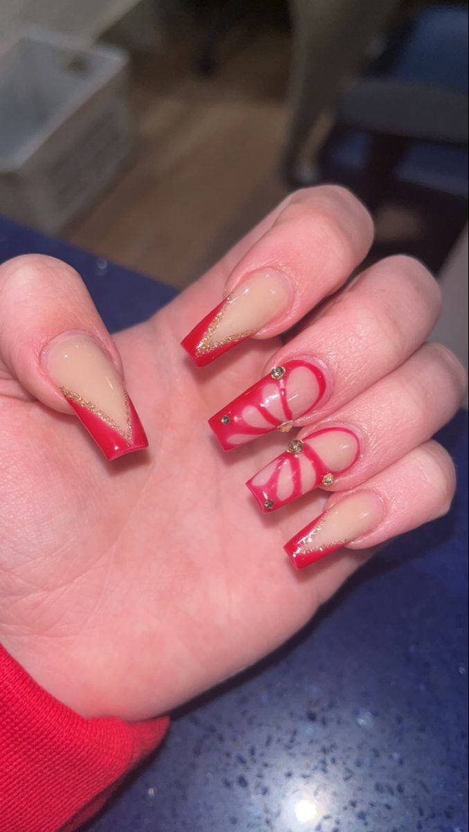 Elegant Red and Nude Nail Design with Intricate Patterns and Gemstone Accents.