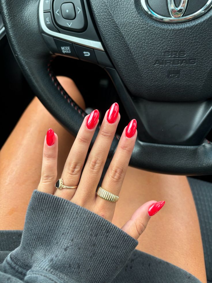 Bold Glossy Red Nail Design Enhances Elegance with Gold Ring Accents.