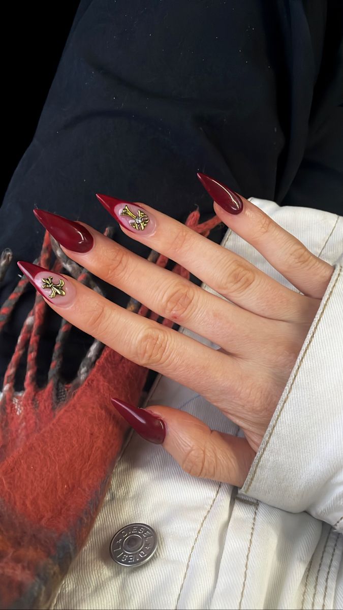 Elegant Burgundy Almond-Shaped Nails with Intricate Gold Embellishments.