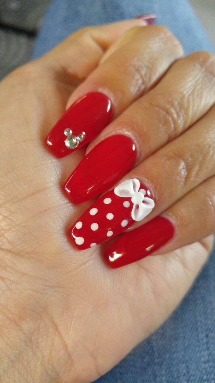 Chic Festive Manicure: Vibrant Red Nails with Whimsical Designs and Sparkling Accents.