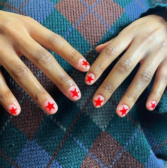 Chic Whimsical Nail Design: Soft Pink Base with Bold Red Star Motifs