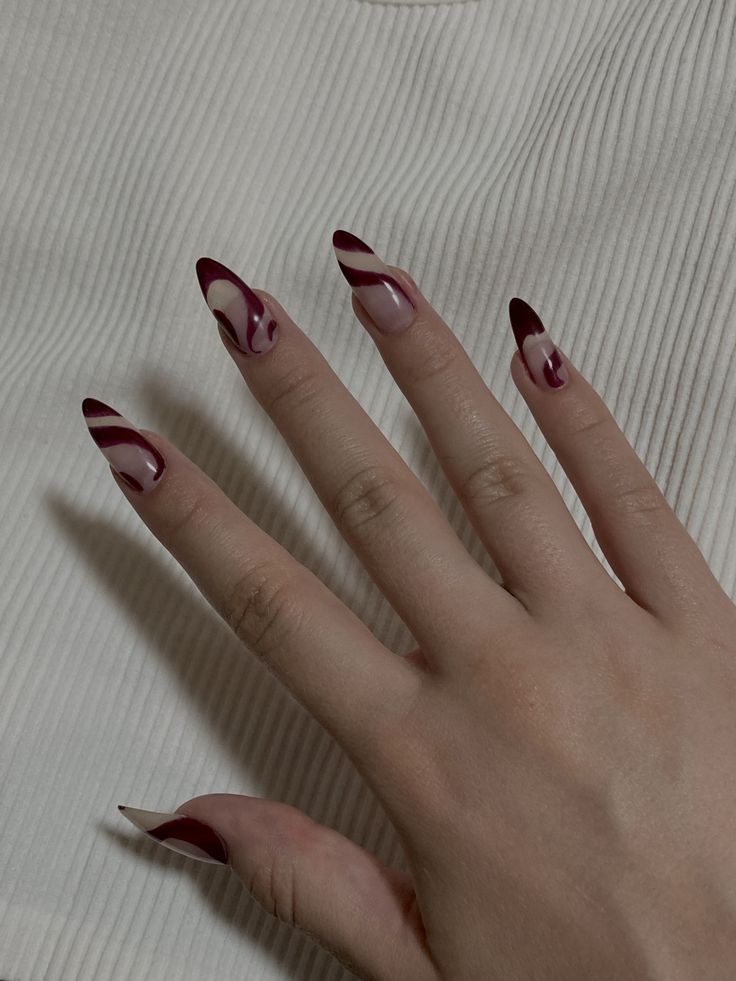 Bold Stiletto Nail Art: Deep Burgundy and Soft Nude with Eye-Catching Swirls.