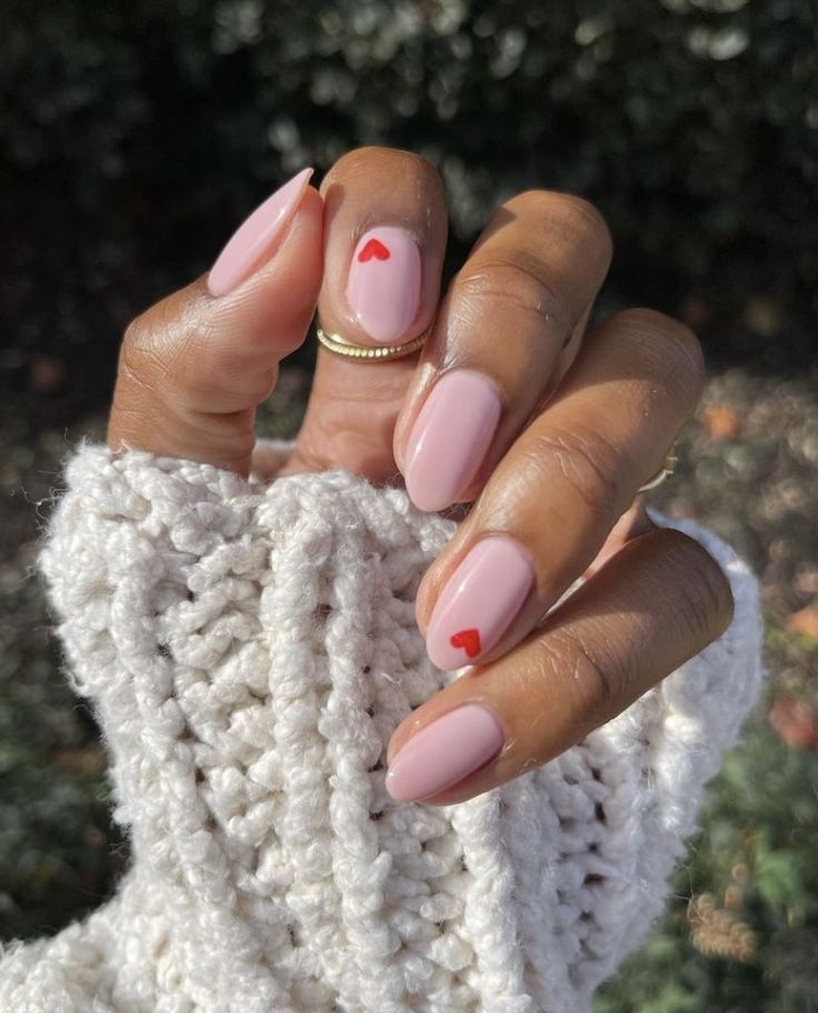 Charming Delicate Nail Design: Soft Pink Base with Tiny Red Hearts for a Cozy, Sophisticated Look.