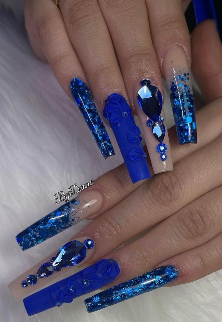 Captivating Long Blue Nail Design with Intricate Embellishments and 3D Accents.