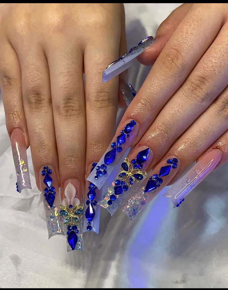 Glamorous Stiletto Nail Design with Translucent Blue Hues and Rhinestone Embellishments.