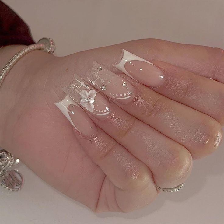 Sophisticated Feminine Nail Design: Soft Pink and Elegant White Tips with Pearls and Floral Accents.