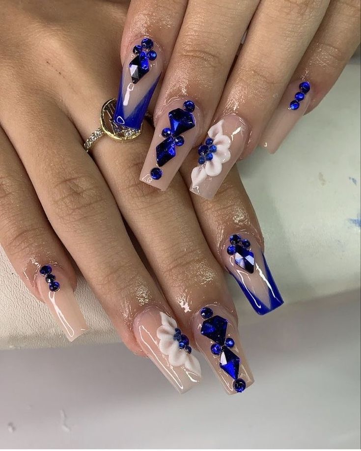 Elegant Nail Design: Nude and Vibrant Blue with Floral Accents and Gemstones