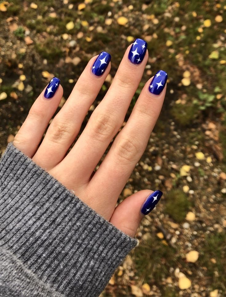 Whimsical Blue Star-Themed Nail Design: Vibrant Royal Background with Chic White Motifs.