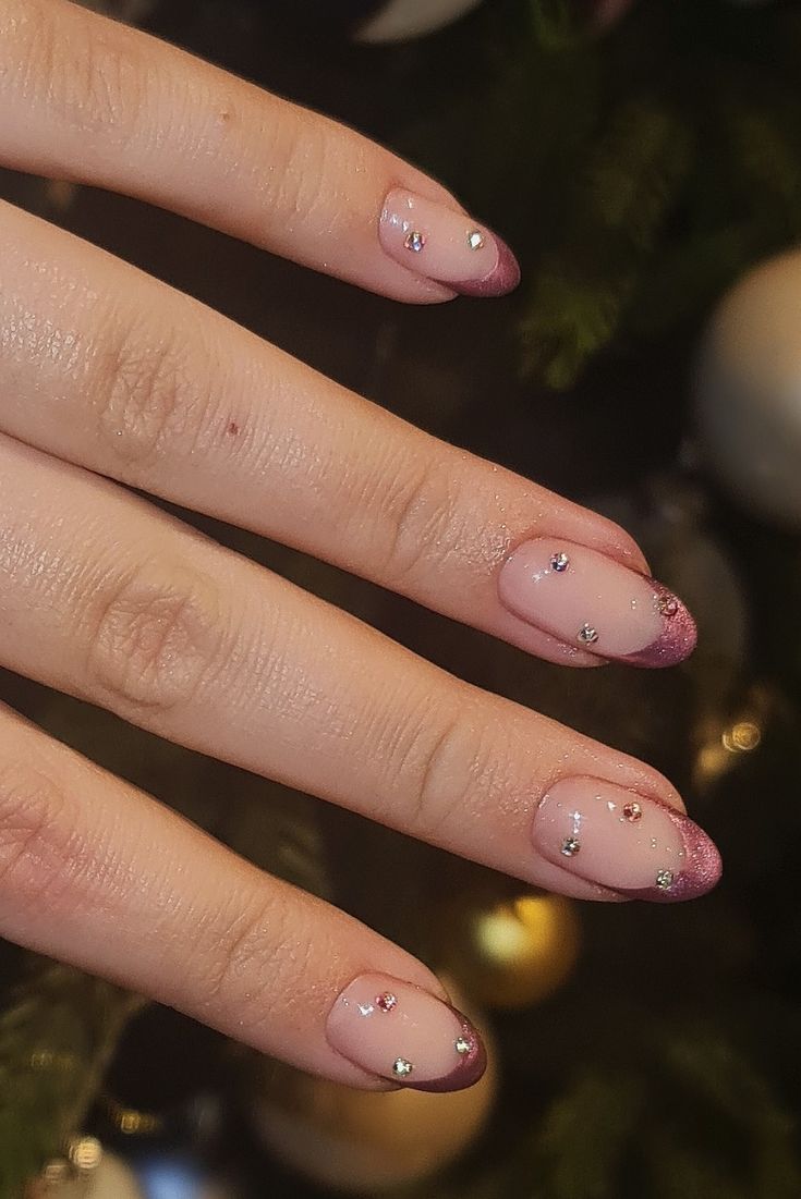 Chic Nude and Soft Pink Nail Design with Glittery Burgundy Tips and Gemstone Accents.