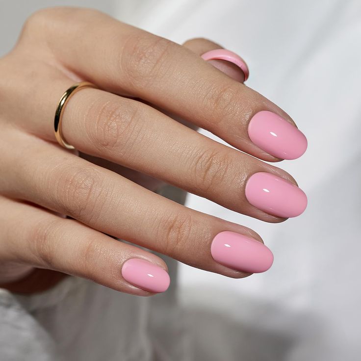 Elegant Soft Pink Manicure with Glossy Oval Nails and Sophisticated Gold Ring.