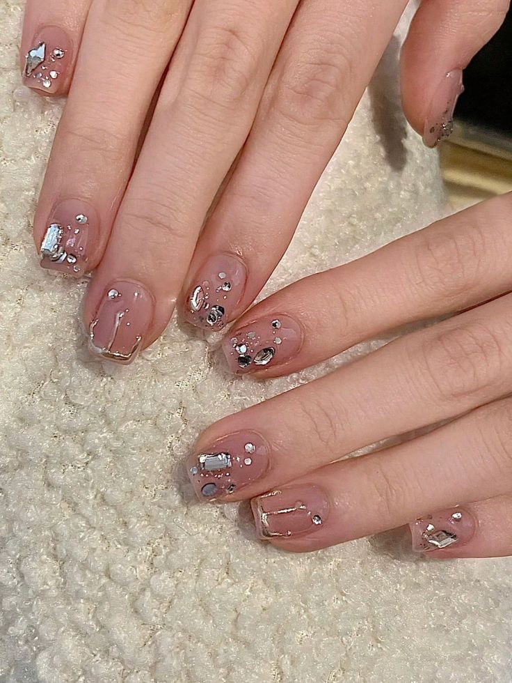 Elegant Nude Nail Design with Metallic Accents and Playful Shapes.