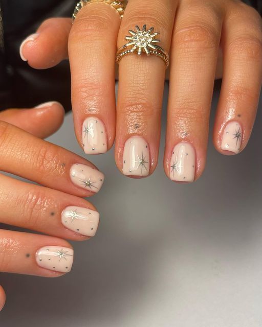 Chic Nude Nail Design with Delicate Silver Stars and Whimsical Dot Accents.