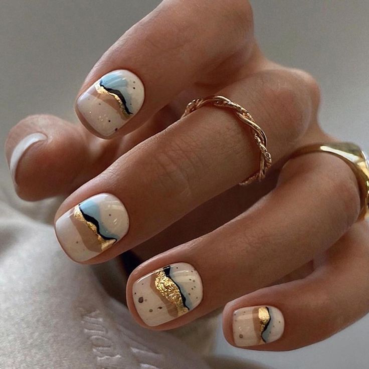 Chic White Nail Design with Fluid Blue and Gold Wave Patterns.