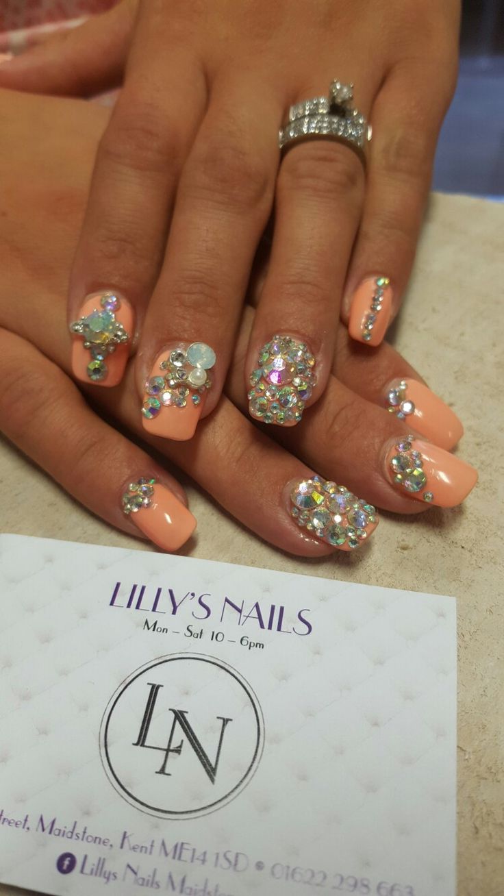 Elegant Peach Nail Design Adorned with Sparkling Rhinestones and Playful Gem Accents